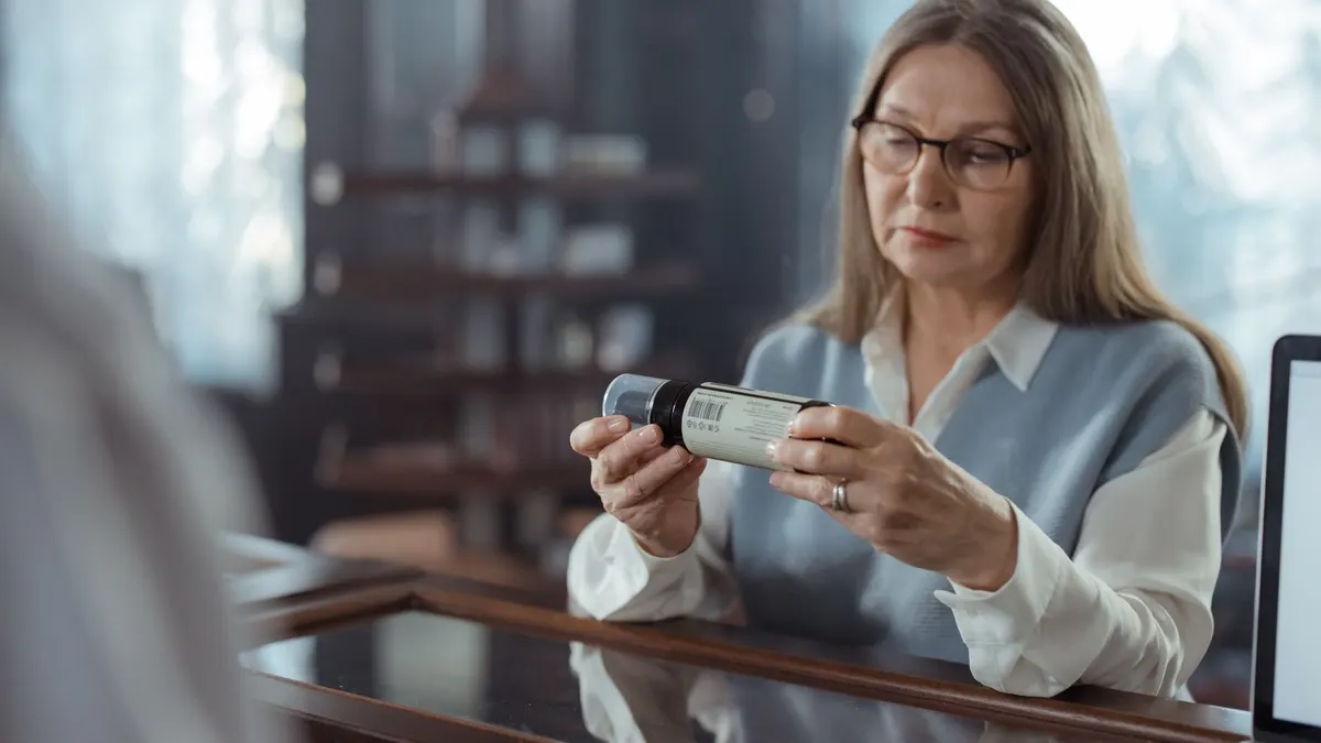 Older adult reading a supplement label before taking it