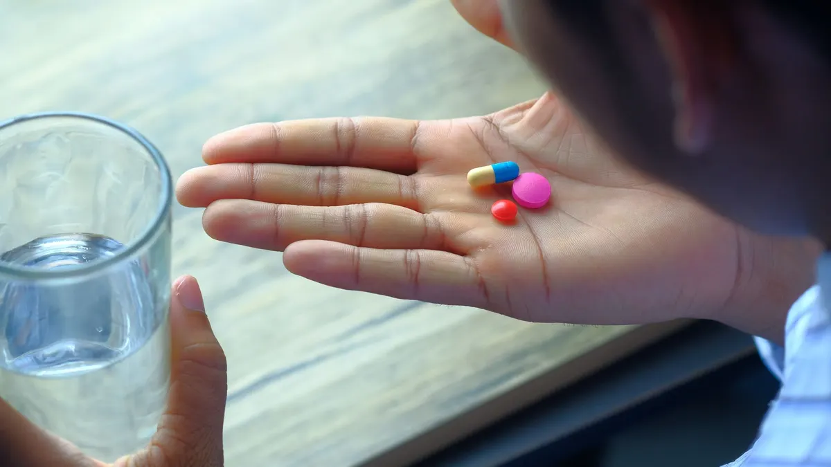 Older woman taking a vitamin B12 supplement with water
